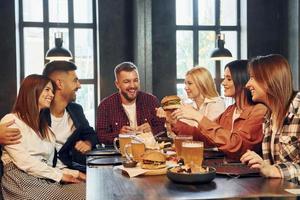 Feeling joy. Group of young friends sitting together in bar with beer photo