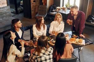 Nice mood. Group of young friends sitting together in bar with beer photo