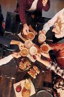 emociones alegres. grupo de jóvenes amigos sentados juntos en el bar con cerveza foto