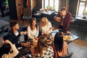 Nice mood. Group of young friends sitting together in bar with beer photo