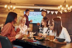 Descansando. grupo de jóvenes amigos sentados juntos en el bar con cerveza foto