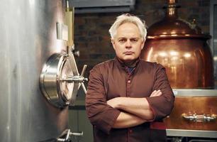 Retro style. Senior man is standing in the storage with equipment for beer photo