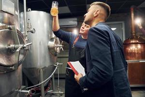 Senior man and young worker with document is standing in the storage beer room photo