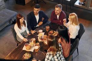 Eating and drinking. Group of young friends sitting together in bar with beer photo