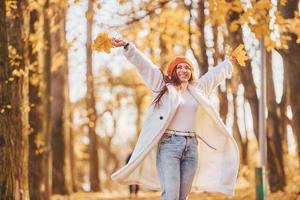 In red beret. Woman in white coat having fun in the autumn park photo