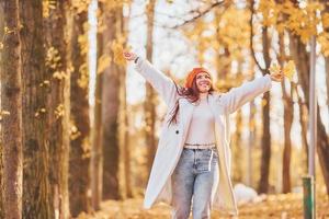 Woman in white coat having fun in the autumn park photo