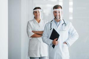 vista frontal. dos médicos con batas blancas están en la clínica trabajando juntos foto