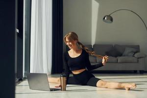 Using laptop. Woman in sportive clothes doing yoga indoors photo