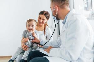 The little boy is being examined. Two doctors in white coats is in the clinic working together photo