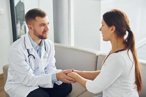 Holding patient by hands. Professional medic in white coat is in the clinic photo