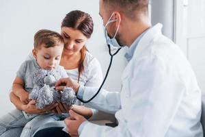 Helping the child. Two doctors in white coats is in the clinic working together photo