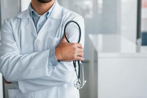 Stethoscope in hands. Professional medic in white coat is in the clinic photo