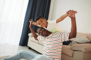 Active weekend time spending. African american father with his young son at home photo