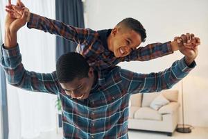 Having fun. African american father with his young son at home photo