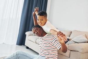 Active weekend time spending. African american father with his young son at home photo