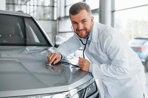 Medic in white coat is using stethoscope on the automobile photo