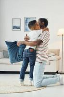 Holding pillows. African american father with his young son at home photo