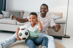 Entertainment for people. African american father with his young son at home photo
