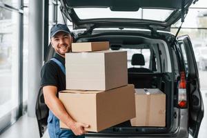 tres cajas el repartidor en uniforme está adentro con auto y con orden foto