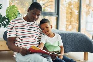 en habitación doméstica. padre afroamericano con su hijo pequeño en casa foto