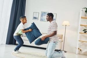 Holding pillows. African american father with his young son at home photo