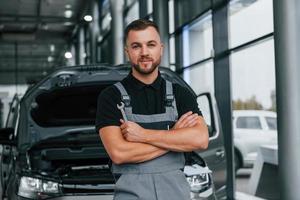 brazos cruzados. el hombre uniformado está trabajando en el autosalón durante el día foto