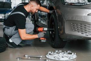 cambio de llantas. el hombre uniformado está trabajando en el autosalon durante el día foto