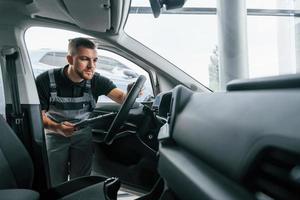 mirando dentro del coche. el hombre uniformado está trabajando en el autosalón durante el día foto