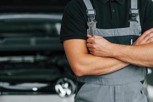 cerca del coche. el hombre de uniforme está trabajando en el autosalón durante el día foto