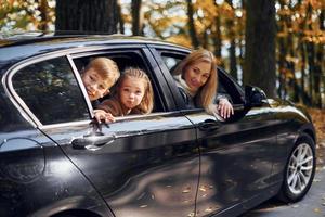 en el coche la familia feliz está en el parque en otoño juntos foto