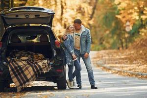 Opened trunk. Couple standing on the road in park near automobile photo