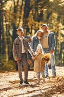 vista frontal. la familia feliz está en el parque en otoño juntos foto