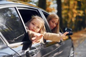 la niña con su madre está sentada en el automóvil y mirando afuera foto