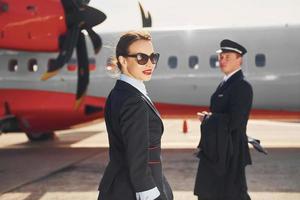 piloto y azafata. tripulación de trabajadores del aeropuerto y del avión con ropa formal de pie juntos al aire libre foto