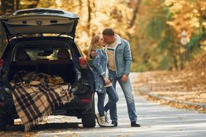 Opened trunk. Couple standing on the road in park near automobile photo