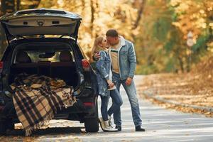 maletero abierto. pareja de pie en la carretera en el parque cerca del automóvil foto