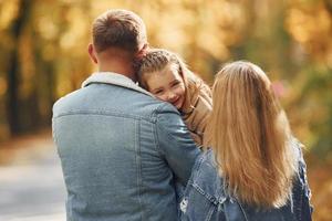 niña con sus padres. la familia feliz está en el parque en otoño juntos foto