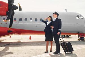 piloto y azafata. tripulación de trabajadores del aeropuerto y del avión con ropa formal de pie juntos al aire libre foto