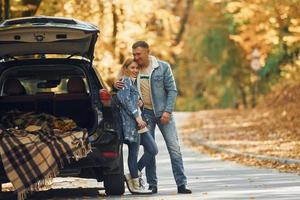 maletero abierto. pareja de pie en la carretera en el parque cerca del automóvil foto