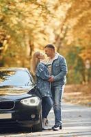 Couple standing on the road in park near automobile photo
