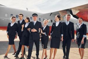 cerca del avión. tripulación de trabajadores del aeropuerto con ropa formal de pie juntos al aire libre foto