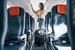 With lugagge. Young female passanger in casual clothes is in the plane photo