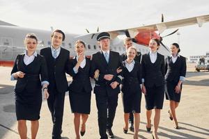 Crew of airport and plane workers in formal clothes standing outdoors together photo