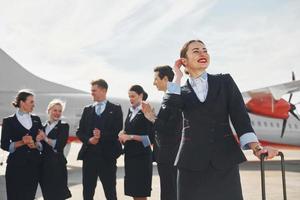tripulación de trabajadores del aeropuerto y del avión con ropa formal de pie juntos al aire libre foto