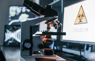 Close up view of modern microscope indoors in lab with monitors. Conception of coronavirus photo