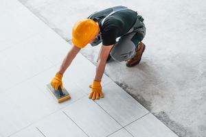 Installation of plates. Man in grey uniform and orange hard hat works indoors in modern big office at daytime photo