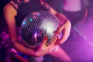 hermosa joven diviértete, bailando en el club nocturno. sosteniendo la pelota de fiesta foto