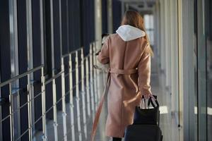 Young female passenger in warm clothes walking with her dog in airport hall photo