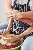 With her boyfriend or husband. Close up view of young female ceramist that indoors with handmade clay product. Conception of pottery photo