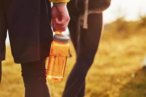 Close up view of couple that walking outdoors. Man holds bottle with water photo